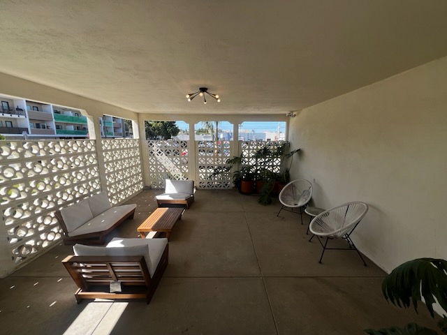 Furnished courtyard lounge with mid-century chairs and sofa behind the restored breeze-block screen
