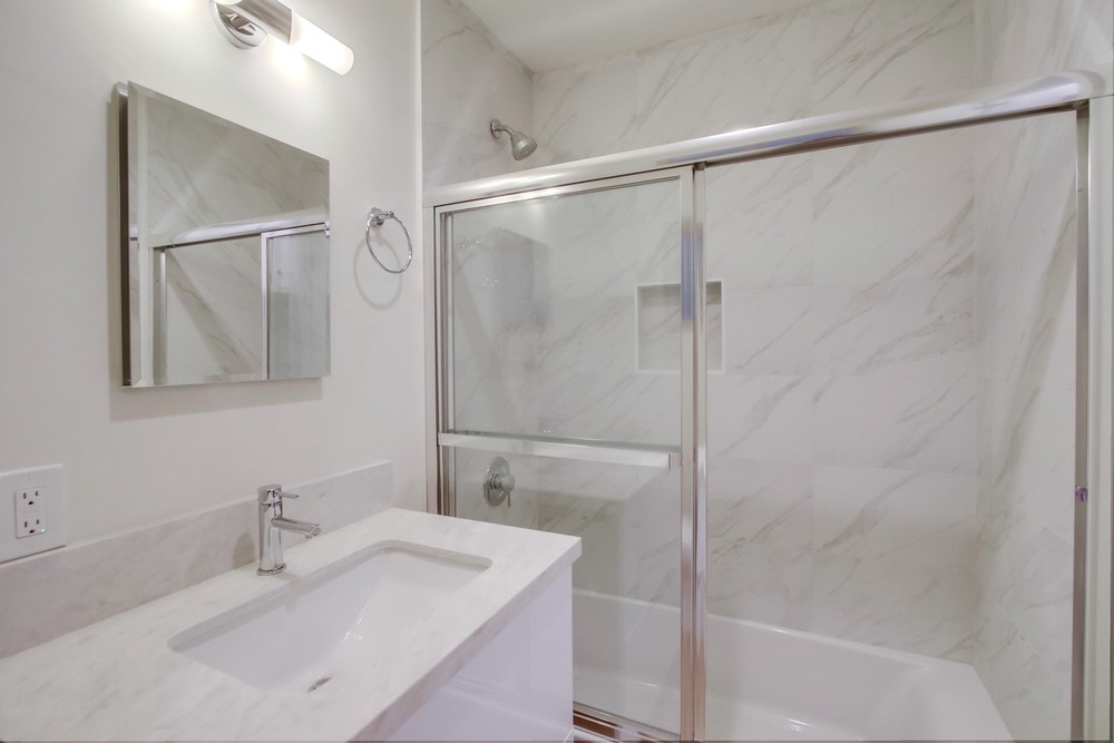 Vacant bathroom with marble-look tile and frameless glass shower