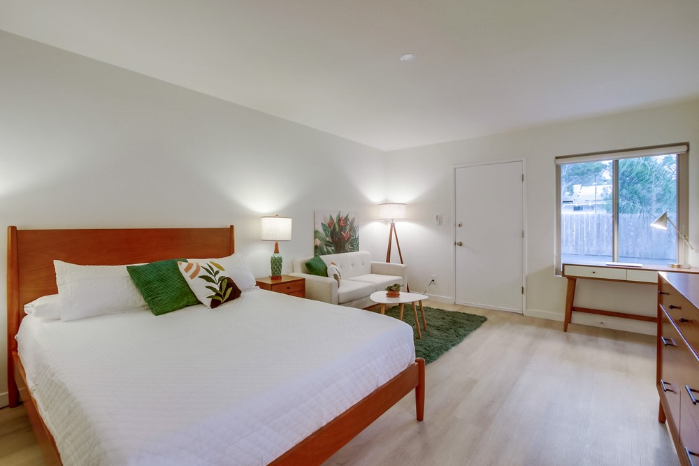 Spacious staged bedroom with walnut platform bed, lounge chair and reading nook