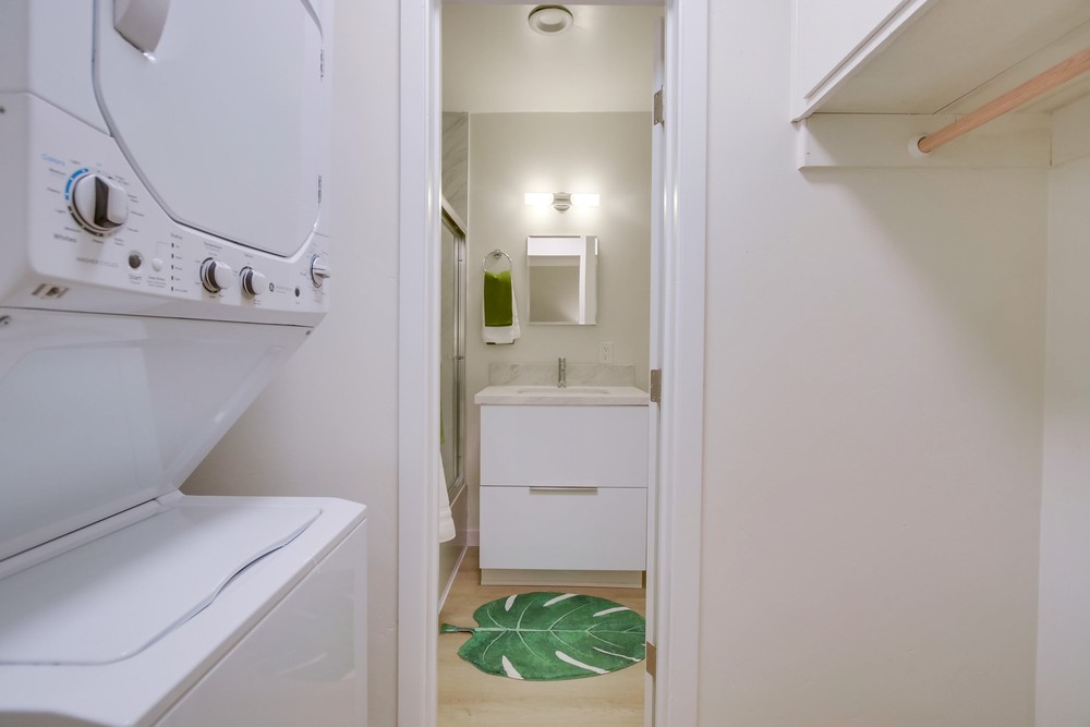 In-unit stacked washer and dryer beside the bathroom and closet